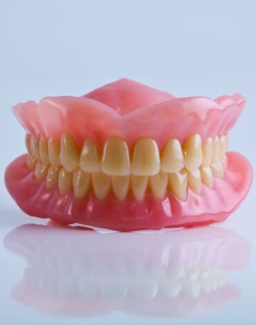 Ağız içine yerleştirilen hareketli protezin yapısını ve kullanım şeklini gösteren bilgilendirici dental görsel.